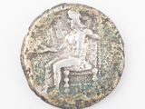 an old silver coin with a man sitting on a bench
