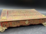 un coffret richement décoré, rouge et or, posé sur une table