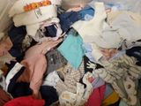 a pile of clothes that is sitting on a bed