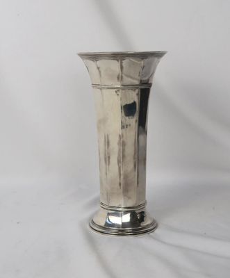 un vase en argent posé sur une surface blanche