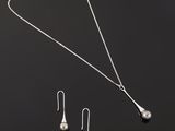 un ensemble composé d'un collier et de boucles d'oreilles en argent sur fond noir