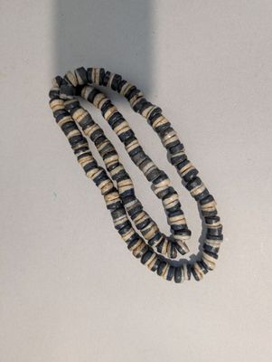 un gros plan d'un collier de perles sur une surface blanche