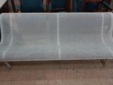un banc en métal blanc dans une pièce où se trouvent des chaises bleues