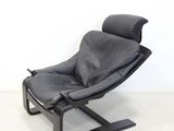 a black leather lounge chair in a white room with a white wall