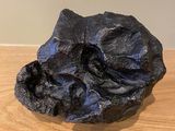 a close up of a black rock on a wooden table