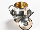 a silver bowl with a lid sitting on a white surface