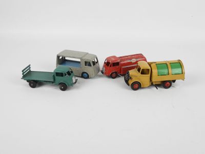 quatre camions miniatures posés les uns à côté des autres sur une surface blanche