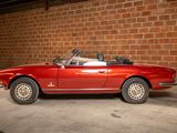 an image of a red convertible car parked in front of a brick wall