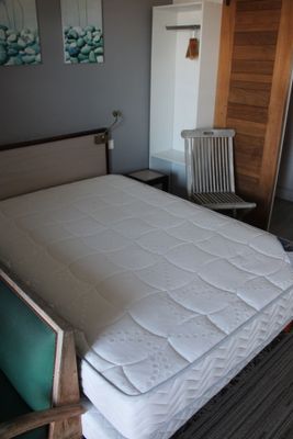 un lit avec un matelas et une chaise dans une chambre