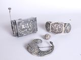 trois bijoux en argent posés sur une surface blanche