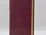 a red book with gold trim and a brown cover on a white background