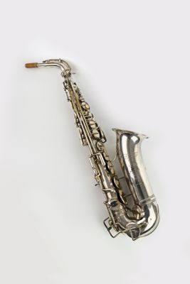 un saxophone argenté posé sur une surface blanche