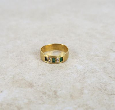 a close up of a gold ring with emerald stones