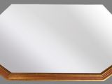 an octagonal mirror with a gold frame on a grey background