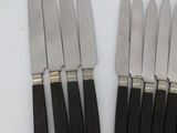 six knives are lined up in a row on a white surface