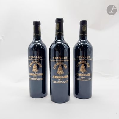 trois bouteilles de vin rouge posées l'une à côté de l'autre sur une surface blanche