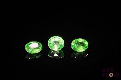 a group of three green gems sitting on top of a black surface