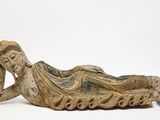 une vieille statue représentant une femme allongée sur le dos sur une surface blanche