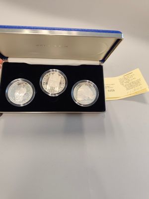 two silver coins in a box with a yellow ticket