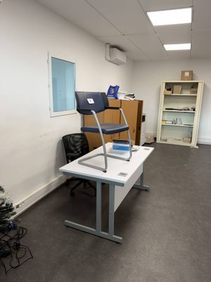 a desk with a chair and a laptop on it in an office