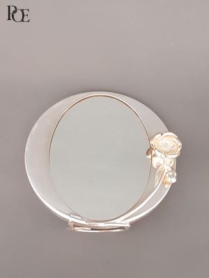 un petit miroir orné d'une fleur, posé sur une table
