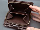 someone is holding a wallet with a zipper open on a table