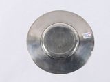 a silver plate on a white surface with a sticker on it