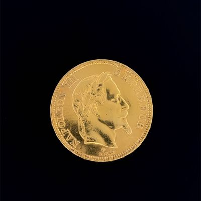 La pièce d'or repose sur une surface noire, sur fond noir.