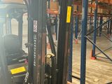 a forklift in a warehouse with a lot of pallets