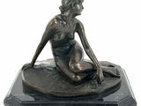 bronze statue of a woman sitting on a rock on a marble base