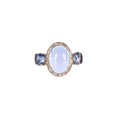 un gros plan d'une bague sertie d'une pierre blanche et de saphirs bleus