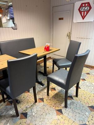 une table et des chaises dans un restaurant, avec une enseigne accrochée au mur