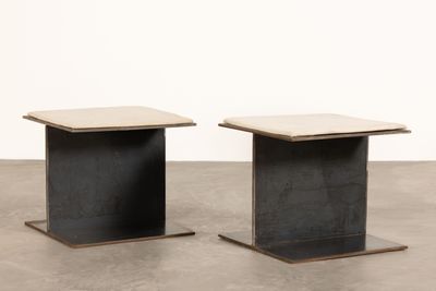 une paire de tables en béton noir et blanc posées sur un sol en ciment