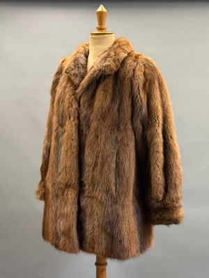 a brown fur coat sitting on top of a wooden mannequin