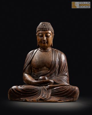 une statue en bois représentant un Bouddha assis sur un fond noir