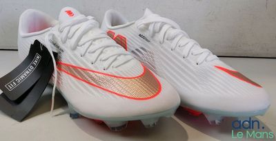 une paire de chaussures de foot blanches et orange posées sur une table