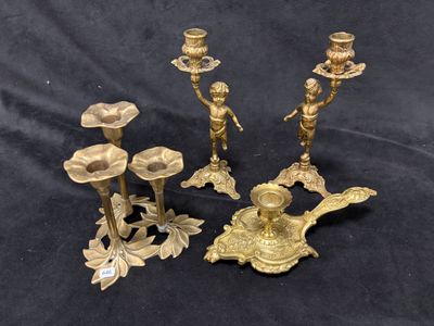 trois bougeoirs en laiton et un porte-bougie sur fond noir