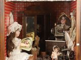 a doll house with dolls in it and a doll in the window