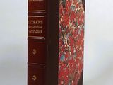 un vieux livre à la couverture rouge posé sur une table blanche