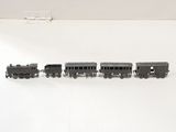 quatre petits trains miniatures alignés sur une surface blanche