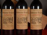 three bottles of red wine are lined up on a table