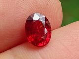 a close up of a red diamond on a person ' s finger
