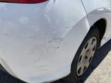 the rear end of a white car with scratches on it