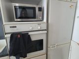 a dog that is standing in the kitchen next to a refrigerator