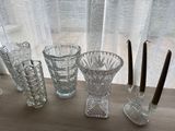 several glass vases and candles sit on a table near a window