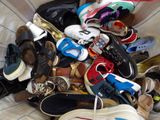 many pairs of shoes sitting in a basket on the bed