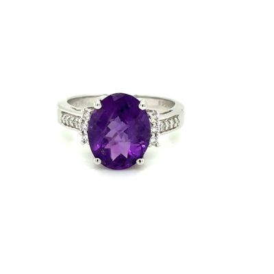 a close up of a ring with a purple stone and diamonds