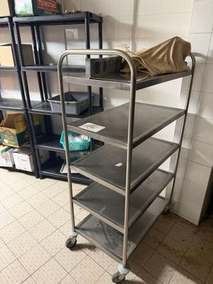a metal cart with four shelves and a bag on top