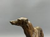 bronze statue of a dog on a pedestal against a gray background