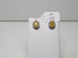 une paire de boucles d'oreilles jaunes et blanches posées sur un présentoir blanc